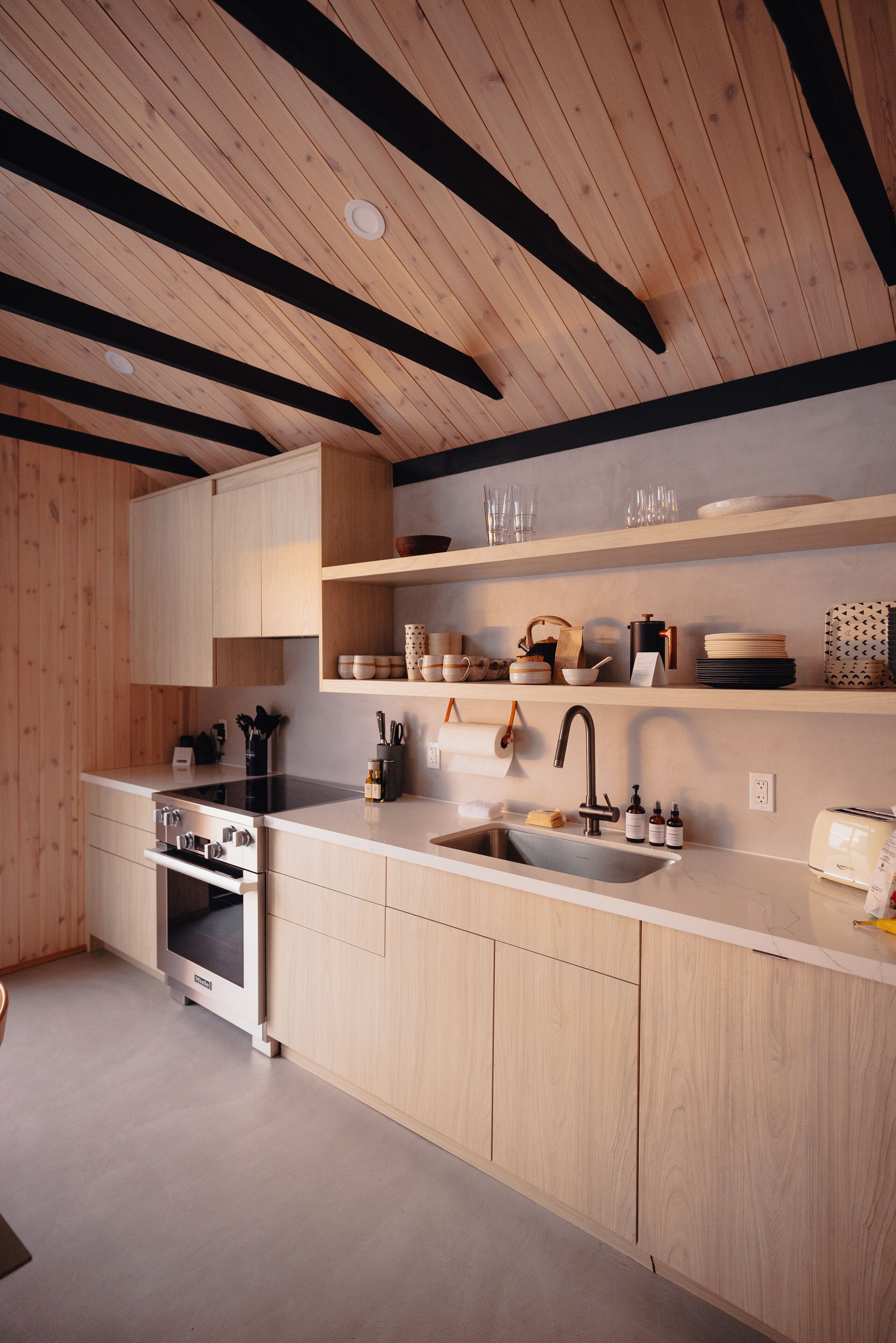 A modern kitchen with wooden cabinets, a stainless steel sink, and a built-in oven.