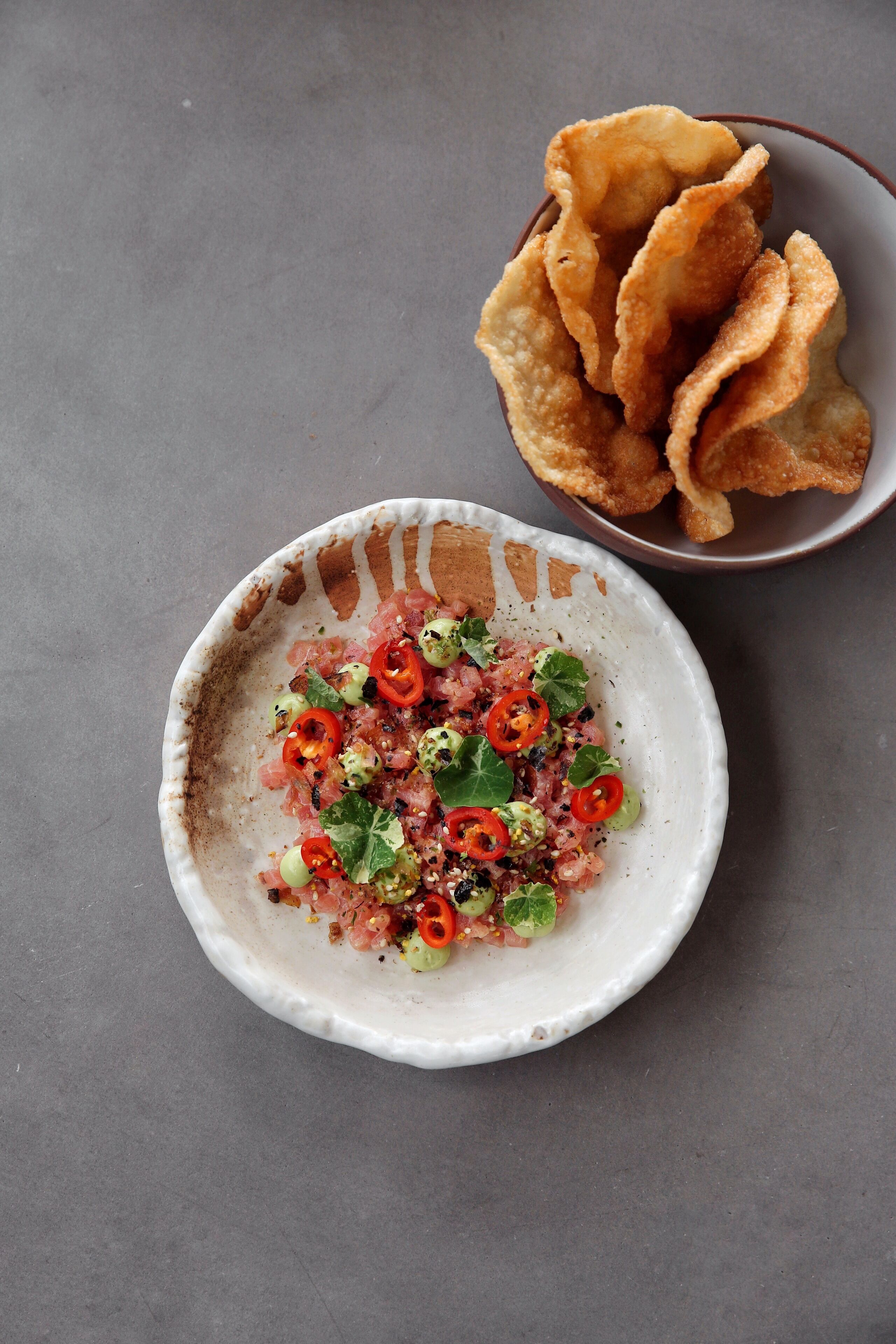A bowl of food with a side of crispy snacks.