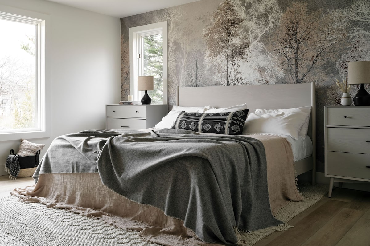A bedroom with a bed, bedside tables, a nightstand, a window, and a textured wall.