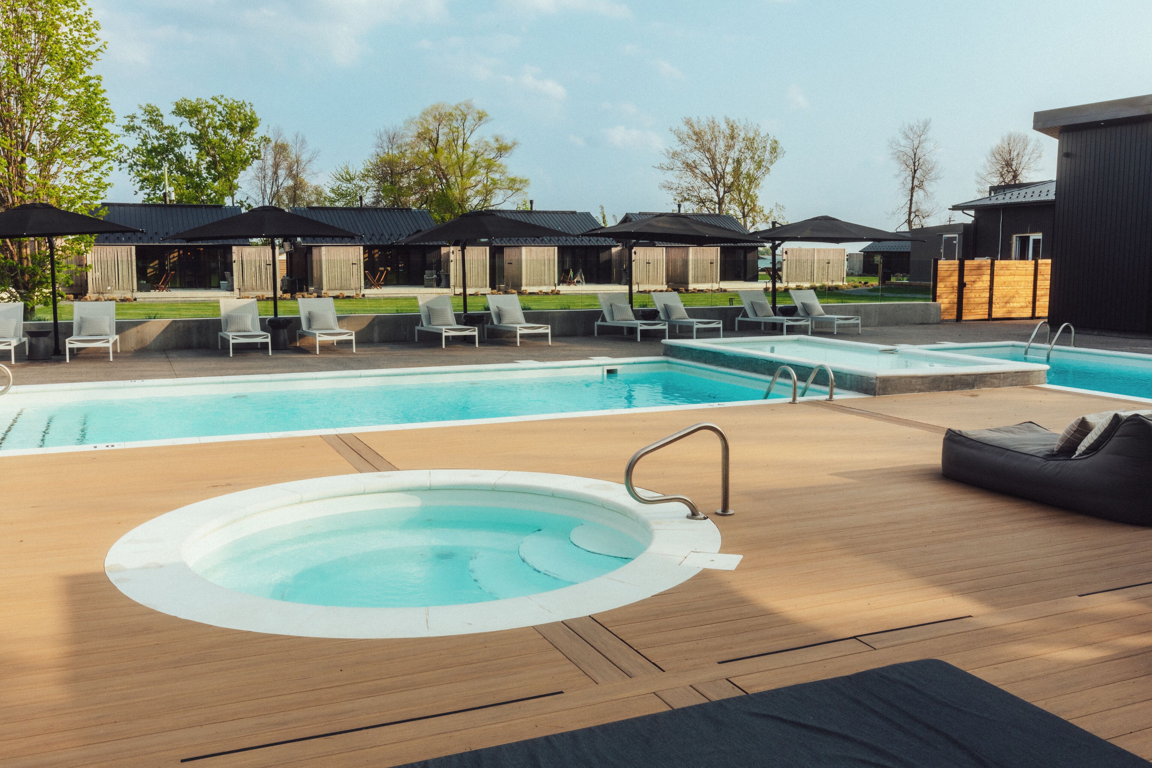 A pool area with lounge chairs, a hot tub, and covered seating areas.