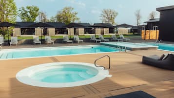A pool area with lounge chairs, a hot tub, and covered seating areas.