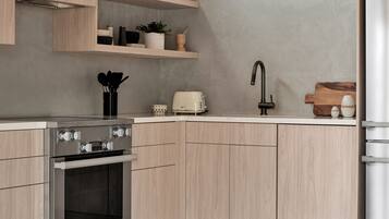 A modern kitchen with wooden cabinets, a built-in oven, and a stainless steel refrigerator.
