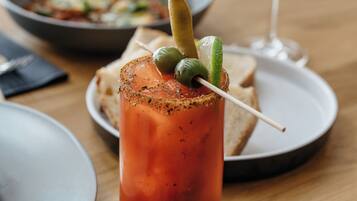 A dining table with a Bloody Mary, a glass of wine, and a plate of food.