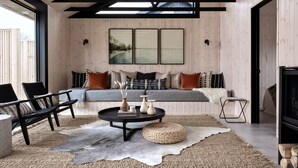 A modern living room with a wooden ceiling, a sofa with cushions, a coffee table, and a television. - Wander the Resort (Prince Edward)