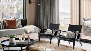 A modern interior with a wooden ceiling, large windows, a sofa, two chairs, a coffee table, and a rug. - Wander the Resort (Prince Edward)
