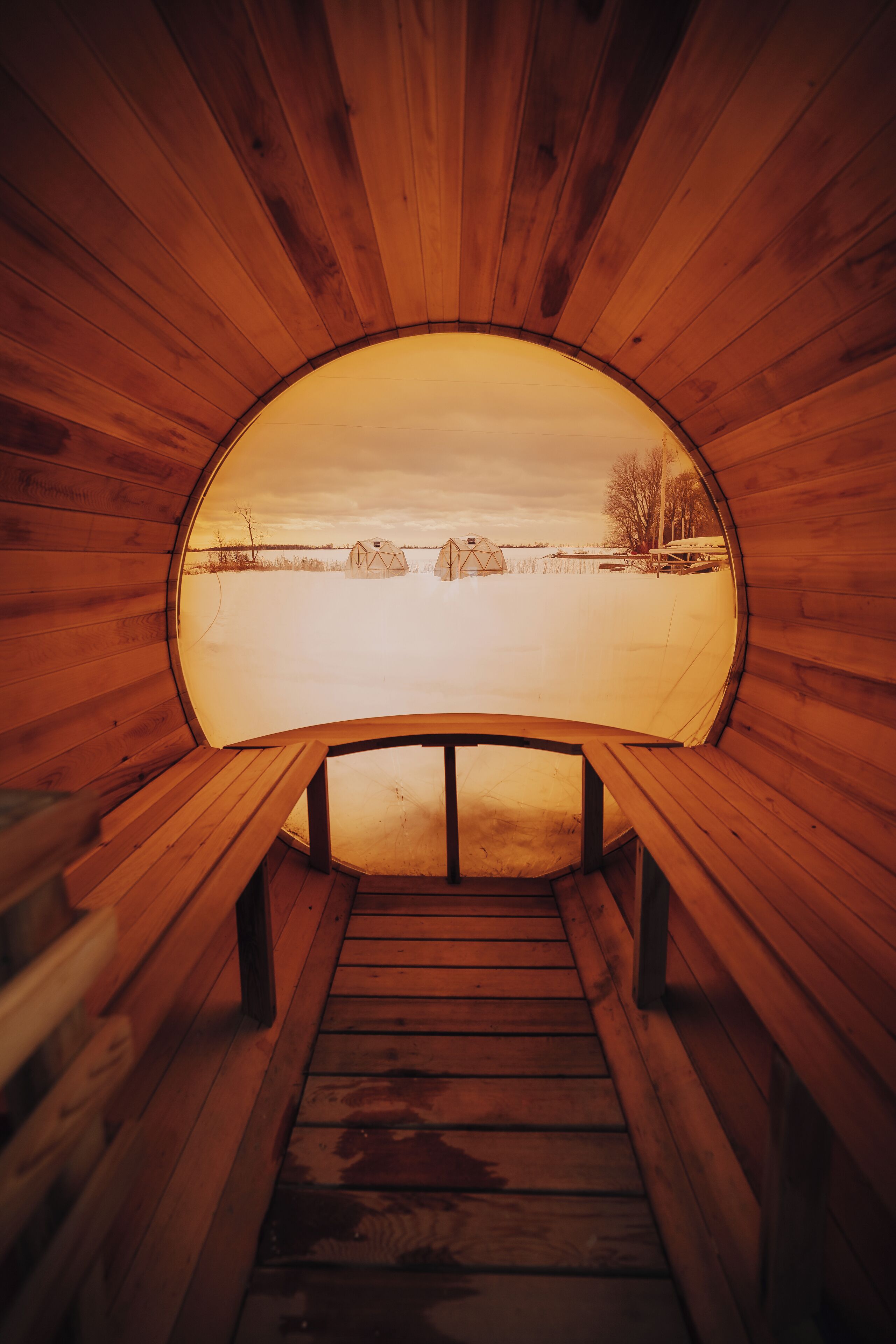A wooden sauna with benches and a view of a snowy landscape.