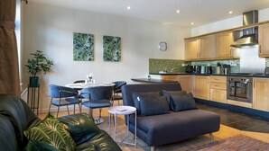A modern living space with a sofa, chairs, a dining table, and a kitchen area with cabinets and appliances. - Stunning 2BR Apt with Balcony Next to Queens Uni - Pass the Keys (Belfast)