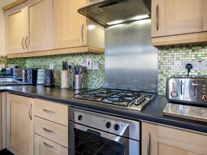 Una cocina con armarios de madera, estufa a gas, tostadora y microondas.