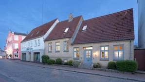 Une rangée de bâtiments de style européen traditionnel, dotés de toits en pente et de petits jardins à l’avant.