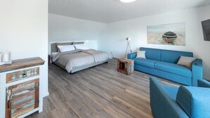 Une chambre à coucher moderne avec un lit, un canapé bleu et une commode en bois.