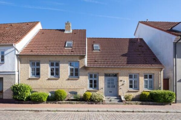 A row of two-story houses with red-tiled roofs, brick walls, and small front gardens. - Large, luxury vacation home with a garden and sauna, located in the heart of Kappeln (Kappeln)