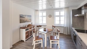 Une cuisine moderne avec une table et des chaises en bois, un four encastré et une fenêtre avec des rideaux.