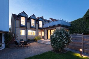 A two-story house with a patio area, a small garden, and a wooden fence. - Large, luxury vacation home with a garden and sauna, located in the heart of Kappeln (Kappeln)