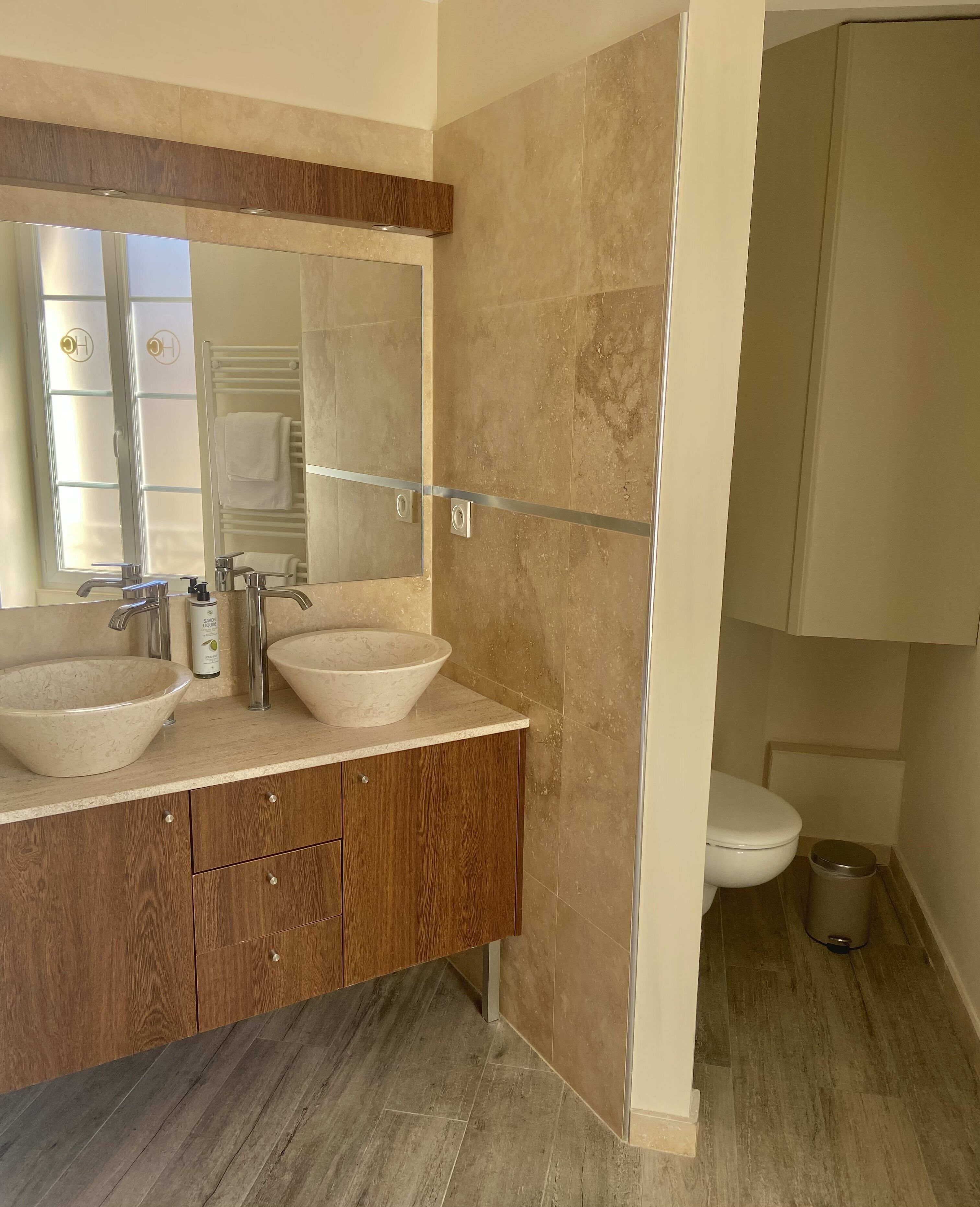 Une salle de bain moderne avec deux grands lavabos, un miroir et des toilettes.