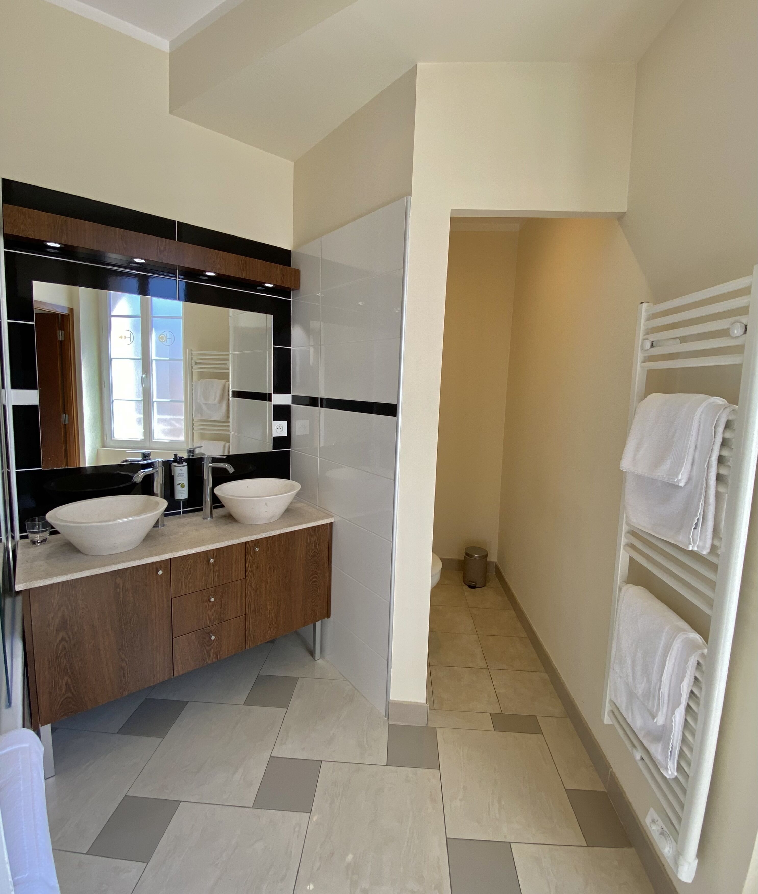 Un baño moderno con dos lavamanos, un espejo grande y un perchero para toallas.