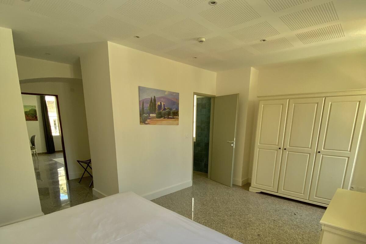 A hotel room with a large bed, a wardrobe, and a painting on the wall.