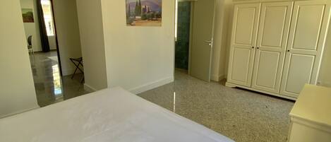 A hotel room with a large bed, a wardrobe, and a painting on the wall.