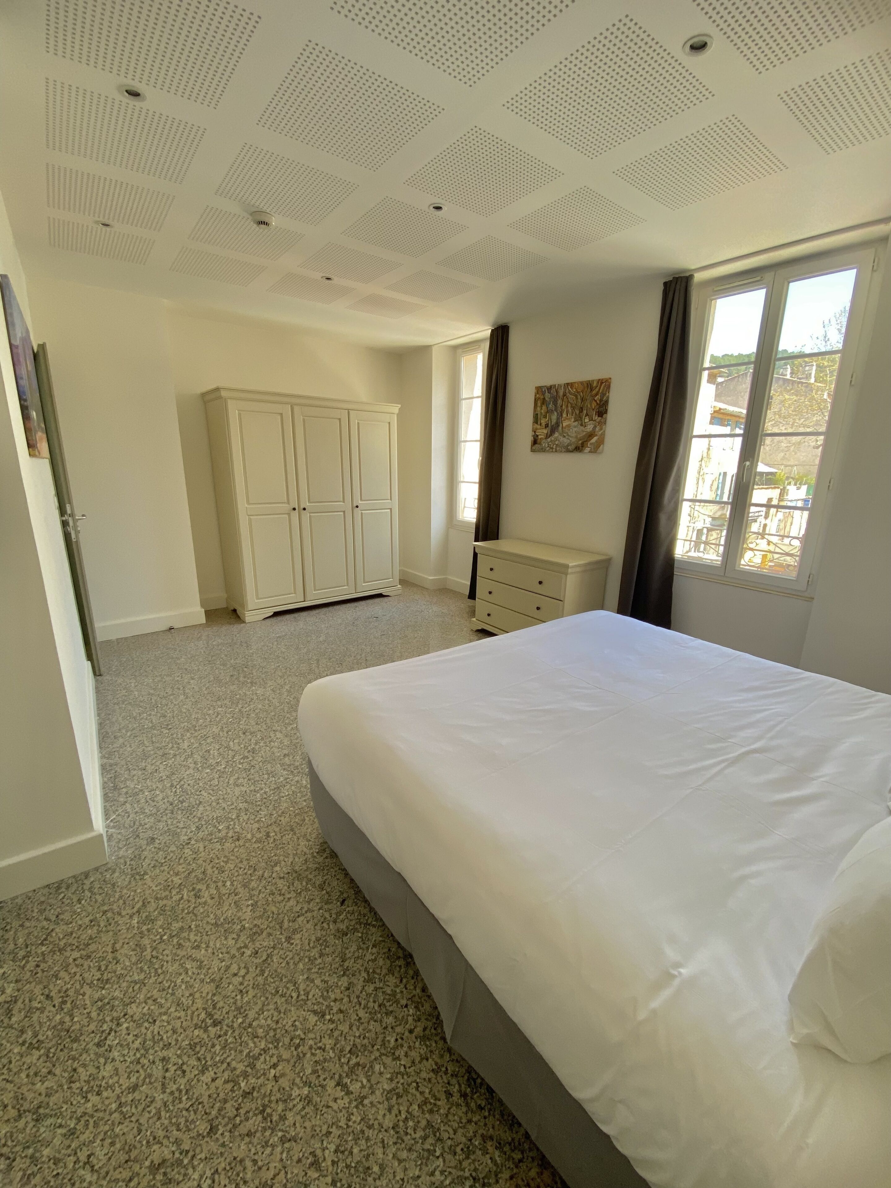 A bedroom with a large bed, a wardrobe, and a dresser.
