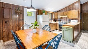 A modern kitchen with wooden cabinets, a central island, and a dining table with chairs.
