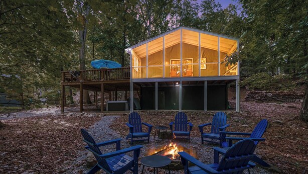 A cabin with a deck, outdoor seating, and a fire pit.