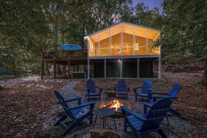 A cabin with a deck, outdoor seating, and a fire pit.