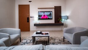 Ett modernt vardagsrum med en platt-TV som är monterad på väggen, en soffa, ett soffbord och en lampa.