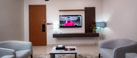 Una sala de estar moderna con un televisor de pantalla plana montado en la pared, un sofá, una mesa de centro y una lámpara.