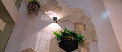 Un intérieur moderne avec des carreaux de sol hexagonaux, des plantes en pot et une prise électrique visible.