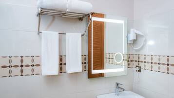 A bathroom with a sink, mirror, towel rack, and hairdryer.