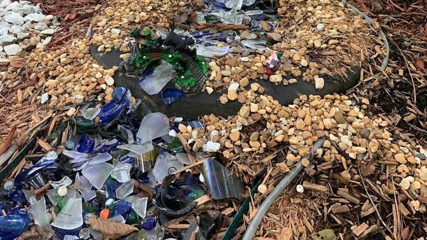 Une scène de forêt avec une petite construction en pierre et un sentier recouvert de verre et de petits cailloux.