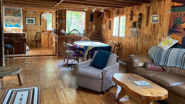 Ein rustikales Blockhaus-Interieur mit Essbereich, einer Couch und einem Couchtisch.