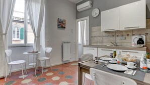 A modern kitchen with white cabinets, a dining table with chairs, and a window with curtains. - APPARTAMENTO SANTI QUATTRO 1 - HOME AND MORE (Roma)