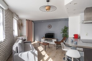 Relax in this stylish living space with a comfortable sofa, modern kitchen, and flat-screen TV.