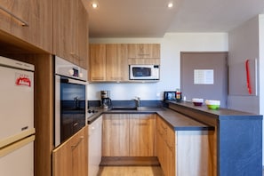 Eine moderne Küche mit Holzausstattung, einer integrierten Mikrowelle, einer Kaffeemaschine und einem Spülbecken.