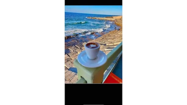 Uitzicht op de kust, met een kop koffie op een hekwerk.