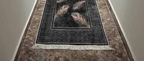 A hallway with a patterned rug leading to a door.