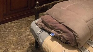 Een slaapkamer met een houten garderobe, een bed met matras en kussens, en een spiegel boven de garderobe.