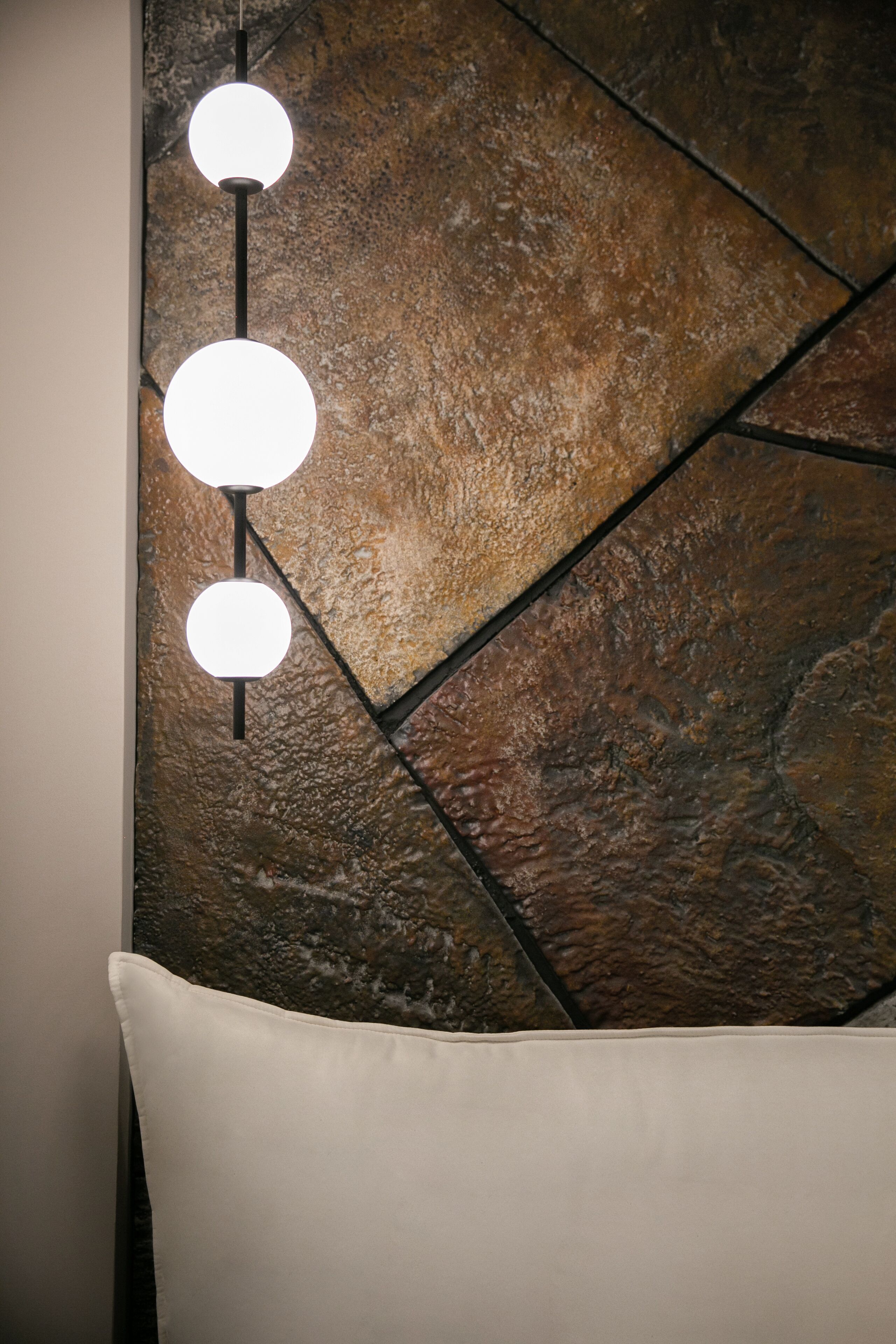 A wall with a textured stone pattern and a series of spherical light fixtures.