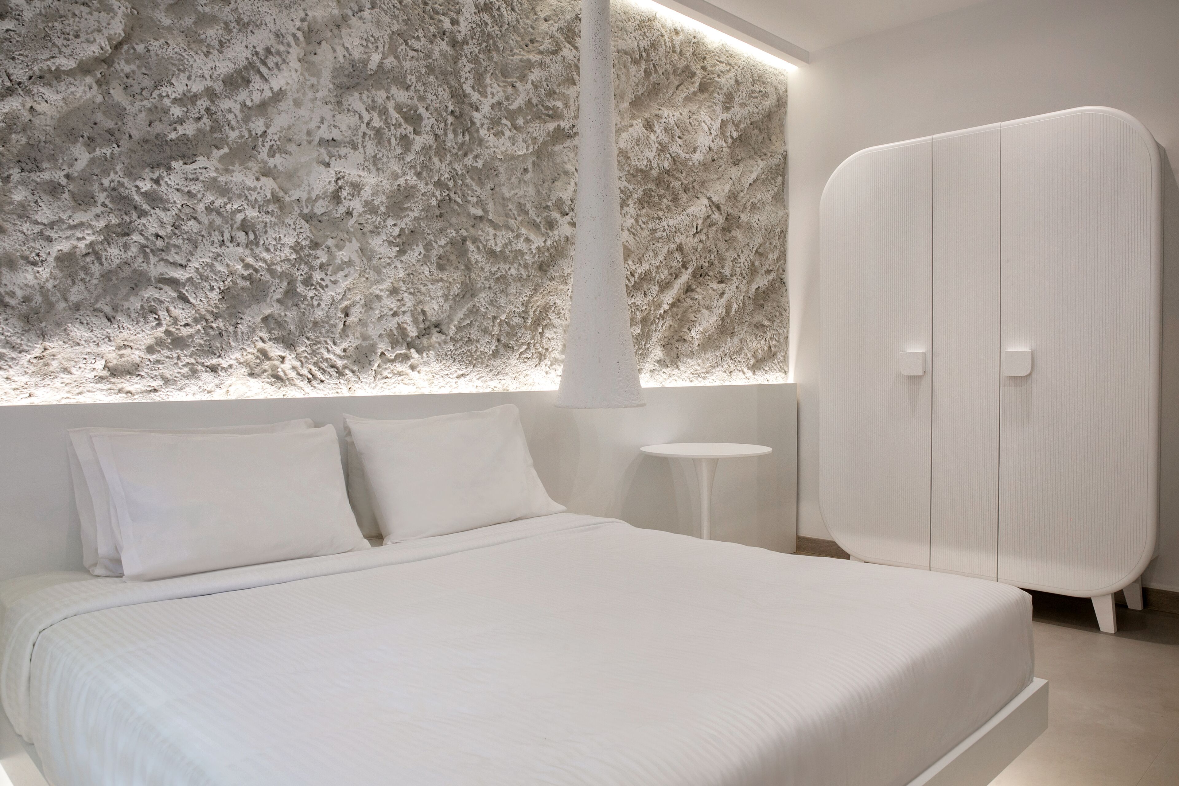 Una camera da letto moderna con un letto grande, un armadio e una parete strutturata.