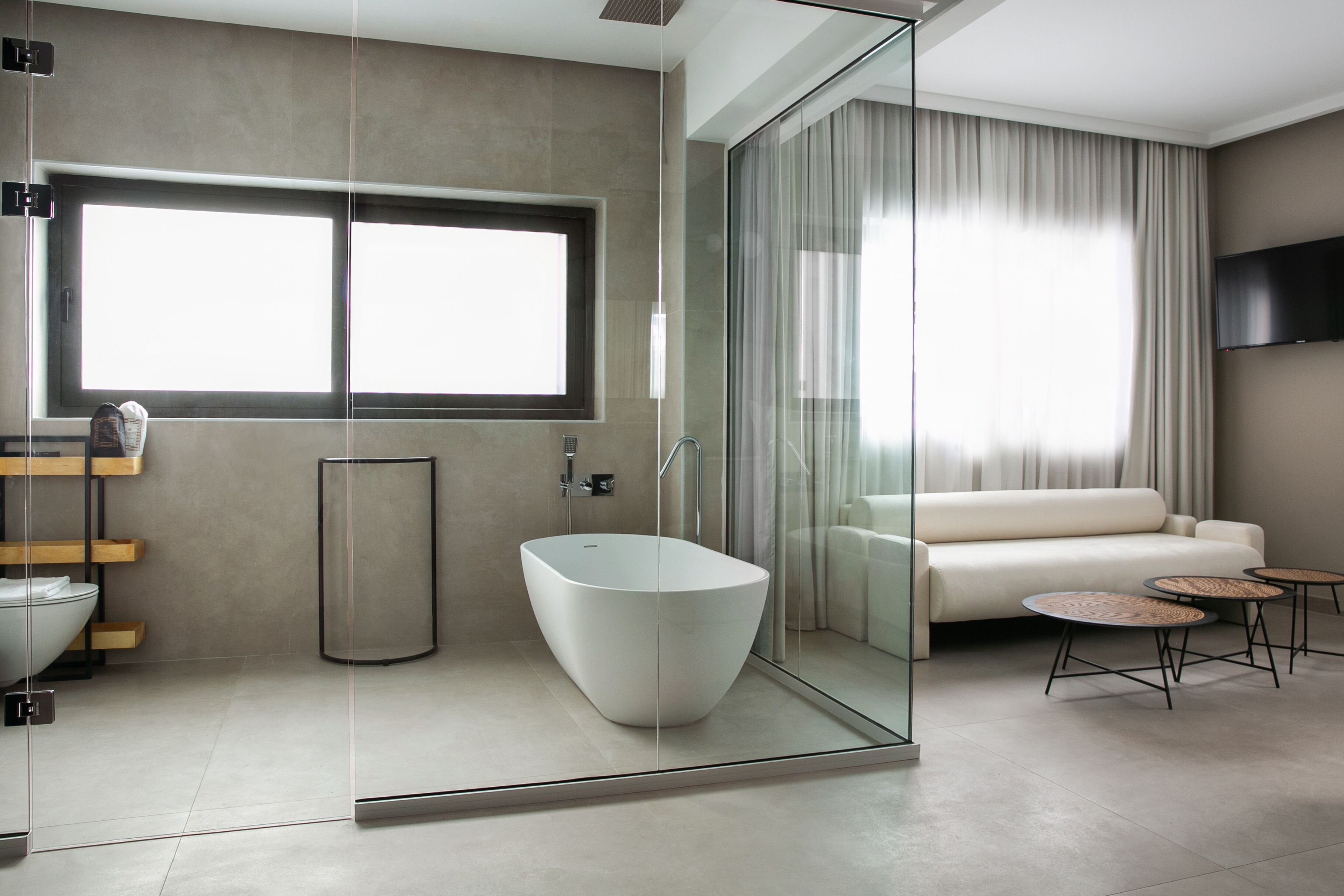 A modern bathroom with a freestanding bathtub, a glass shower enclosure, and a large window providing natural light.