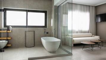 A modern bathroom with a freestanding bathtub, a glass shower enclosure, and a large window providing natural light.