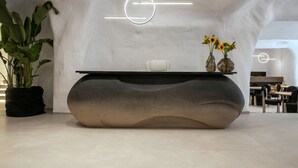 Ein moderner Empfangstresen mit markantem Design, eine Topfpflanze und Vasen mit Sonnenblumen.