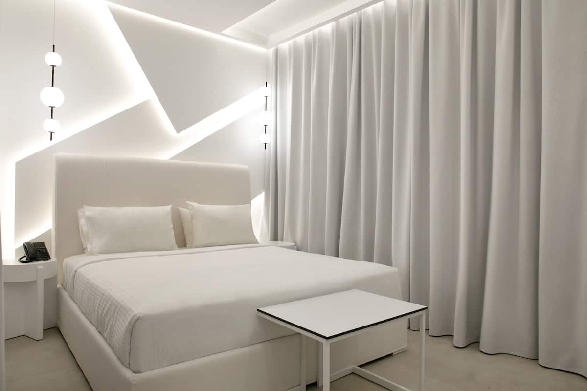 Un dormitorio moderno con una cama grande, mesitas de noche y un buró.