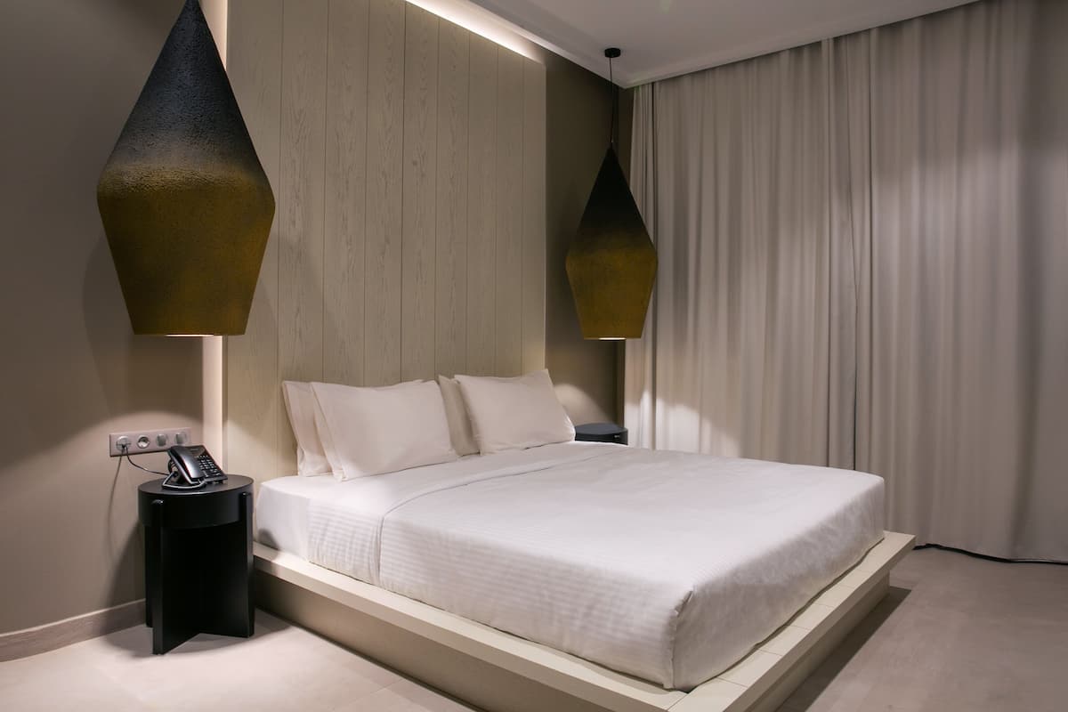 Un dormitorio moderno con cama, mesitas de noche e iluminación colgante.