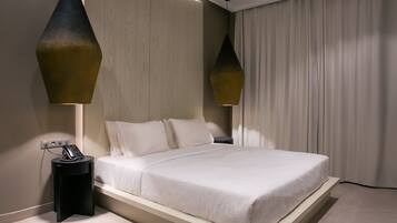 A modern bedroom with a bed, bedside tables, and pendant lights.