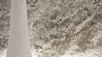 A white textured wall with a textured ceiling and a white table.