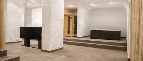 A spacious, modern interior with a minimalist design, featuring a large black piano, a wooden cabinet, and a stone-tiled floor.