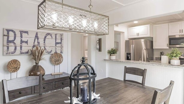 A modern kitchen with white cabinets, stainless steel appliances, and a wooden dining table with chairs.