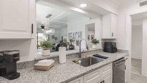 A modern kitchen with granite countertops, a stainless steel sink, and a coffee maker.