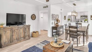 A spacious living room with a television, wooden cabinet, and a ceiling fan.